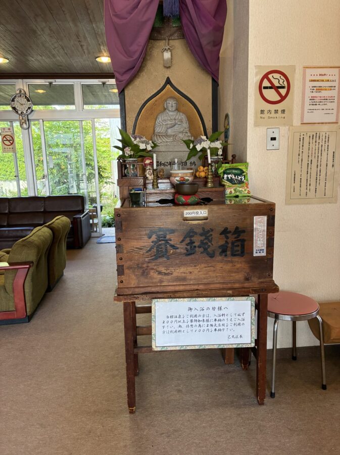 乙丸温泉、玄関内入口の薬師如来。お賽銭箱に入浴料200円を入れる
